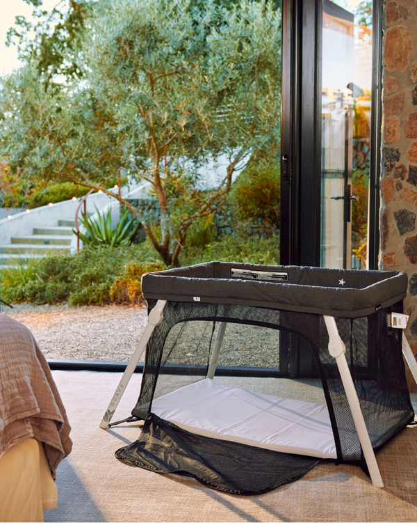 The Lotus Travel Crib set up in a bedroom by a window